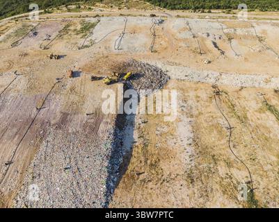 Blick von oben auf die Ablagestelle. Müllwagen. Gelber Traktor. Abfallsortierung. Mülldeponie einer Großstadt Stockfoto