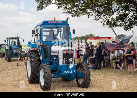 Ein blauer Ford 78-Traktor ohne Straßen, der an einem sonnigen Tag bei einer Traktorrallye auf einer Landmesse gefahren wird. Stockfoto