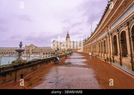 Sevilla Plaza de Espana in Spanien zeigt einen Brunnen unter einem regnerischen Frühlingshimmel, mit kunstvoller Architektur und bunten Fliesen, die den ruhigen Blick unterstreichen Stockfoto