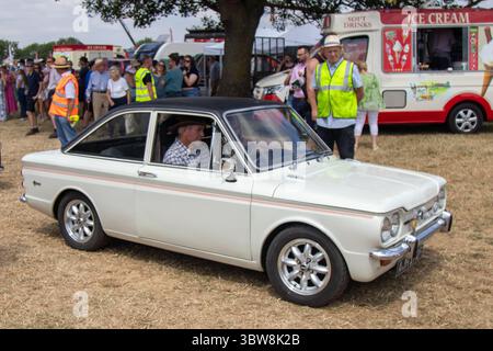 Ein weißes Hillman Imp Cabrio auf einer britischen Landmesse, das während einer Oldtimer-Show an Menschenmassen vorbeigefahren ist, die die britische Automobilgeschichte feiert. Stockfoto