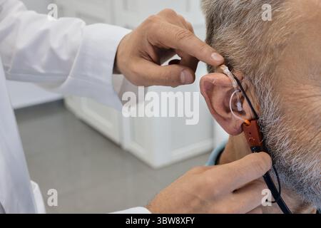 Der Audiologe passt ein Hörgerät an, um das Audioerlebnis eines Einzelnen mit fortschrittlichen Techniken, Nahaufnahme, zu verbessern. Echthaarmessungen Stockfoto