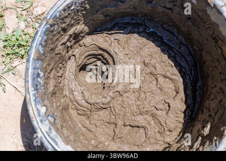 Nahaufnahme eines Eimers mit frischem Mörtel, der für das Verlegen von Ziegeln vorbereitet wird. Stockfoto