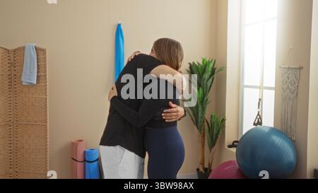 Mann und Frau, die sich in einem Fitnessstudio umarmen, umgeben von Sportgeräten, was auf eine unterstützende Beziehung in einem Fitnessraum hindeutet Stockfoto