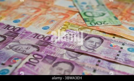 Die philippinischen Banknoten sind verstreut und weisen verschiedene Stückelungen auf, darunter 100-Peso- und 200-Peso-Scheine. Stockfoto