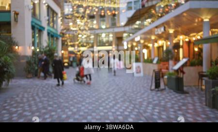 Die Menschen schlendern durch eine festliche londoner Straße mit verschwommenen weihnachtslichtern und Dekorationen am Winterabend im vereinigten Königreich und schaffen einen Stockfoto