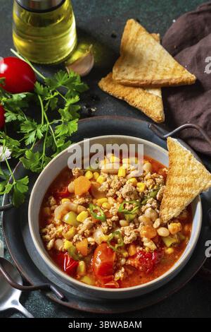 Traditionelle mexikanische Küche. Chili con carne, Hackfleisch mit Gemüse auf dunklem Steintisch Stockfoto