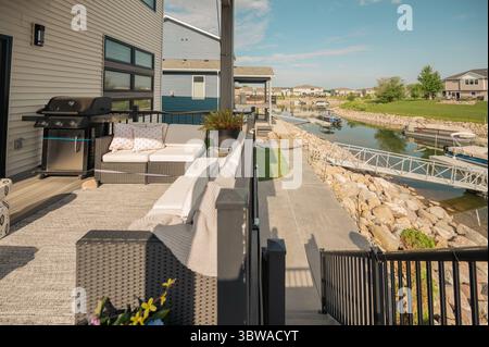 Gemütliche, moderne Terrasse mit Blick auf das Wasser und das grüne Feld Stockfoto