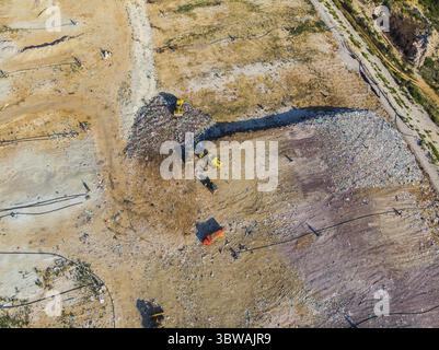 Blick von oben auf die Ablagestelle. Müllwagen. Gelber Traktor. Abfallsortierung. Mülldeponie einer Großstadt Stockfoto