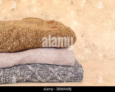 Ein warmer, einladender Stapel Strickpullover in neutralen Farben, perfekt, um die Essenz des Herbst- und Pullover-Wetters zu demonstrieren Stockfoto