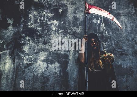 Dämonenhexe mit Sensenmann auf Grunge-Wand-Hintergrund. Halloween und religiöses Konzept. Dämonenengel und Satan Thema Stockfoto
