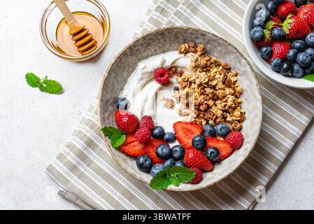 Müslischale für ein gesundes Fitness-Frühstück. Hausgemachtes Müsli mit griechischem Joghurt, frischen Beeren und Honig in Keramikschale, Blick von oben. Gesunde Ernährung Konz Stockfoto