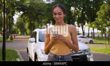 Afroamerikanische Frau mit Handy Smartphone Handy Handy Autofahrer Lächeln Auto Auto Transport Miete Service Straße online weibliches Mädchen Stockfoto
