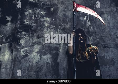 Dämonenhexe mit Sensenmann auf Grunge-Wand-Hintergrund. Halloween und religiöses Konzept. Dämonenengel und Satan Thema Stockfoto