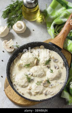 Hausgemachte Fleischbällchen in Sauerrahmsauce mit Pilzen in einer Pfanne auf Stein- oder Schiefertisch Stockfoto