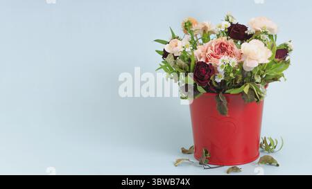 Dies ist ein Strauß welkender Blumen in einem dekorativen Eimer auf blauem Hintergrund. Herbstzeit. Löschen einer Grußkarte mit Platz zum Kopieren Stockfoto