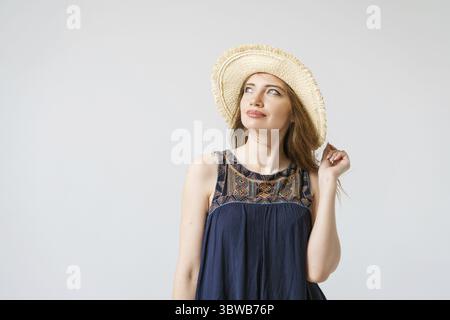 Porträt charmante junge Frau in hellelegantem blauem Kleid und breitem Stroh Stockfoto