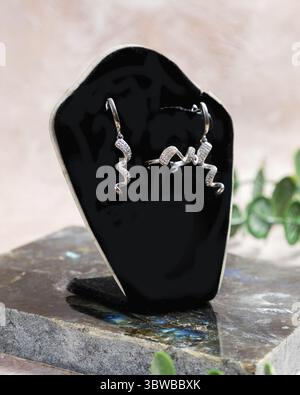 Silberne Ringe und Ohrringe mit einzigartigem Wellendesign werden auf einem schwarzen Schmuckdisplay ausgestellt, das das Glitzern der Diamanten zeigt Stockfoto