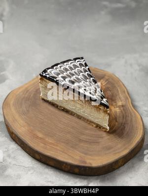Köstliches Stück Kuchen mit Schokoladenglasur auf einem Holzbrett auf grauem Hintergrund Stockfoto