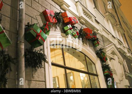 Stilvolle tannenzweige mit roten Kugeln und glitzernder Girlande vor der Tür auf dem Weihnachtsmarkt oder Restaurant in der Stadtstraße. Winterchristma Stockfoto