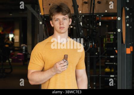 Bodybuilder oder junger Mann, der Energieriegel isst. Muskulöse Sportler Snacks Protein Bar, während sie sich nach dem Training im Fitnessstudio oder Fitnesscenter ausruhen. Stockfoto