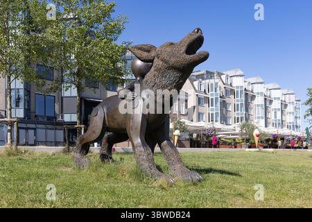 Eine große Bronzestatue eines heulenden Wolfs mit einem kleinen Kind auf dem Rücken namens „Waterwolf en Aquanaut“ neben einer Uferpromenade. Nijmegen, Netherla Stockfoto