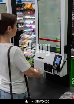 Eine Frau scannt Artikel an einer Selbstkasse. Stockfoto