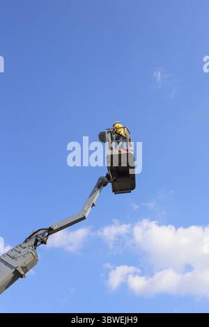 Der Arbeiter befindet sich im Korb des Lifts, hoch in der Luft. Stockfoto