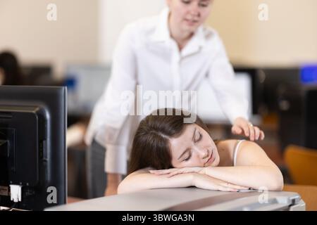 Junge Studentin schläft während der Fortbildung im Computerlabor ein Stockfoto