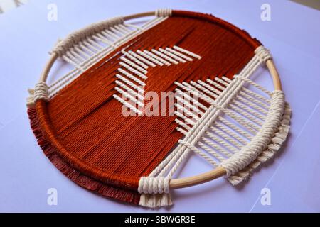 Handgewebte geometrische Wandkunst in Rot und Beige Ein einzigartiger gewebter Wandaufhänger mit einem auffälligen geometrischen Muster in Rot und Beige. Stockfoto