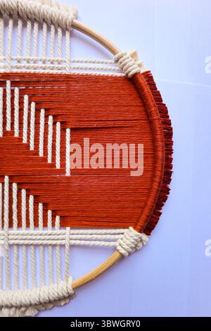 Handgewebte geometrische Wandkunst in Rot und Beige Ein einzigartiger gewebter Wandaufhänger mit einem auffälligen geometrischen Muster in Rot und Beige. Stockfoto