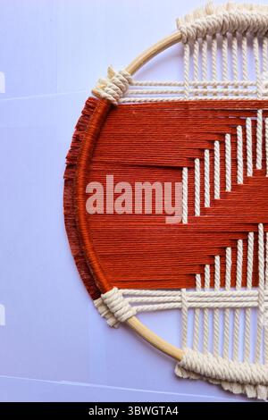 Handgewebte geometrische Wandkunst in Rot und Beige Ein einzigartiger gewebter Wandaufhänger mit einem auffälligen geometrischen Muster in Rot und Beige. Stockfoto