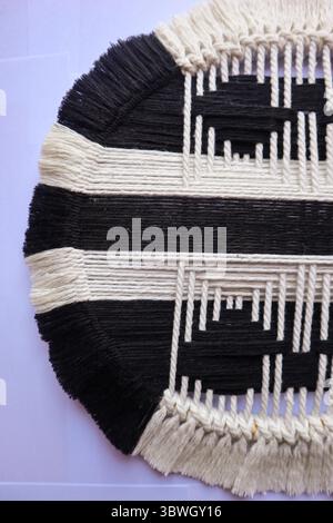 Handgewebte kreisförmige Wandkunst in Schwarz und weiß Ein handgefertigtes, gewebtes Wandkunstwerk in Schwarz-weiß mit modernem geometrischem Design. Stockfoto