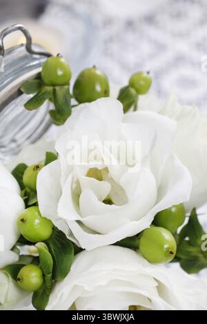 Winziges Bouquet weißer Eustoma-Blüten und grüner hypericum-Pflanze. Partydekor Stockfoto