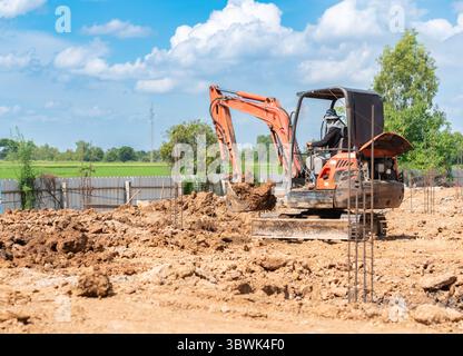Ein Minibagger gräbt Boden im Fundamentarbeitsbereich auf der Baustelle. Stockfoto