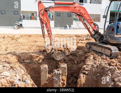 Ein Minibagger gräbt Erde um den Pfahlkopf herum, um den Pfahldeckel vorzubereiten. Stockfoto