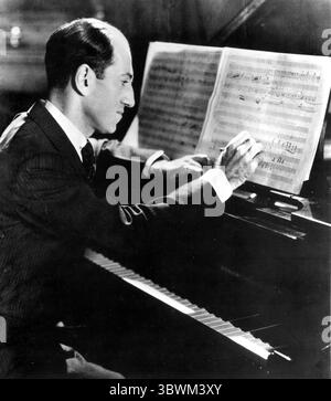 1936, Hollywood, Kalifornien, USA: US-amerikanischer Komponist und Pianist GEORGE GERSHWIN, 36, schrieb einen möglichen Zukunftshit an seinem Klavier. Als Jacob Gershwine am 26. September 1898 geboren, reichten seine Kompositionen über populäre, Jazz und klassische Genres. Zu seinen bekanntesten Werken zählen die Orchesterkompositionen Rhapsody in Blue (1924), an American in Paris (1928), die Lieder Swanee (1919), faszinierender Rhythmus (1924), Embraceable You (1928), I Got Rhythm (1930) und die Oper Porgy and Bess (1935), die den Hit Sommertime enthielt. Kompositionen wurden für Film und Fernsehen adaptiert, viele davon bec Stockfoto