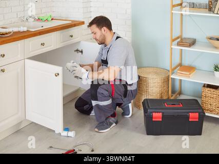 Klempner, professioneller Arbeiter wechselt Rohre unter Waschbecken, passt und repariert Armaturen, Wasserversorgung Stockfoto