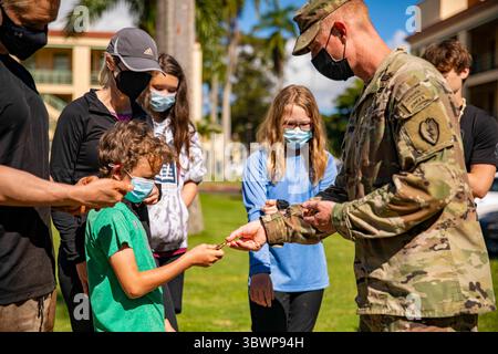 15. März 2021: Schofield Barracks, Hawaii, Vereinigte Staaten – Oberst Joshua Bookout, 3. Infanterie-Brigade Combat Team, 25. Infanterie-Division-Kommandant überreicht am 15. März 2021 eine Brigade-Münze an die Kinder von Ed Ray, einem Mitglied der Gold Star-Familie bei F-Quad, Schofield Barracks Hawaii. Ed Ray ist der Zwillingsbruder von 1. Lieutenant Clovis T. Ray, einem Anführer des Gewehrzuges, der dem 2. Bataillon, 35. Infanterieregiment zugewiesen wurde, als er am 15. März 2012 an Wunden starb, die er während eines feindlichen Angriffs mit einem improvisierten Sprengsatz erlitten hatte, als er auf Patrouille im Pech River in der Provinz Kunar, Afghanistan, starb. (Foto vom 1 Stockfoto