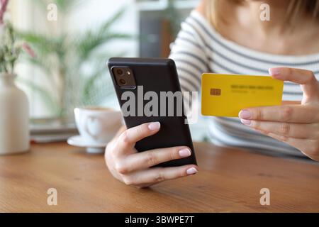 Nahaufnahme Porträt einer Frauenhand, die eine Karte verwendet, um online mit dem Smartphone zu Hause zu kaufen Stockfoto