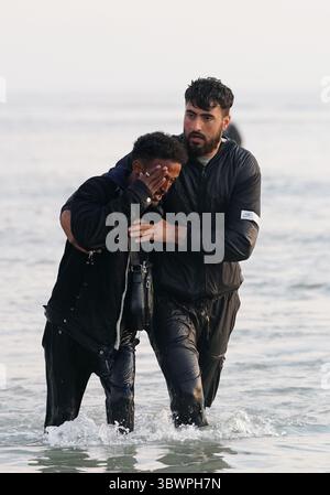 Menschen, die als Migranten gelten, waten ins Meer, um an Bord eines kleinen Bootes in Gravelines, Frankreich, zu gehen. Bilddatum: Donnerstag, 17. Juli 2025. Stockfoto