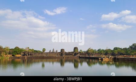 Blick auf den Tempel Angkor Wat, der sich im Wasser unter einem blauen Himmel spiegelt, von der anderen Seite des Grabens in Siem Reap, Kambodscha. Stockfoto