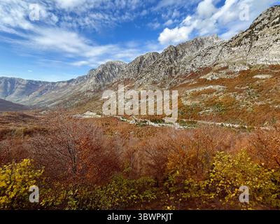 Malerischer Herbstblick auf die Berge und das Tal in Malësi e Madhe, Nordalbanien, mit lebhaftem Laub und zerklüfteten Gipfeln. Stockfoto