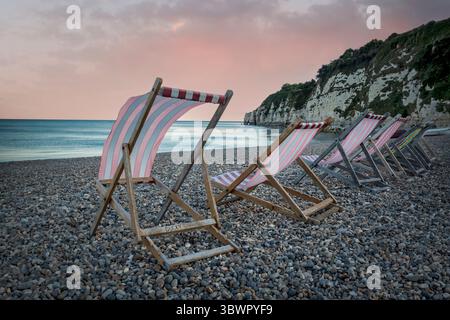 Eine Reihe von Liegestühlen, die in der Meeresbrise in Devon wehen Stockfoto