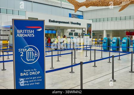 Gepäckabgabebereich am Flughafen mit Schildern von British Airways und Check-in-Automaten Stockfoto
