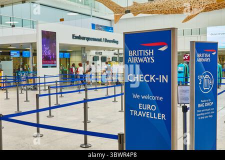 Gepäckabgabebereich am Flughafen mit Schildern von British Airways und Check-in-Automaten Stockfoto