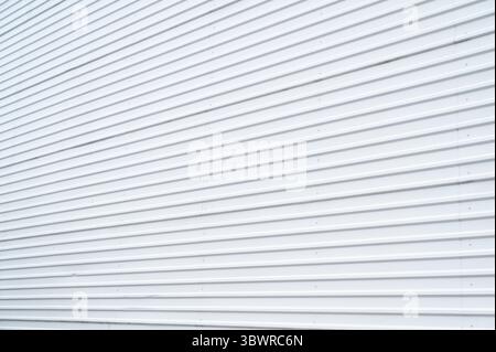 Weiße gewellte Metallwand für einen strukturierten Hintergrund, ideal für industrielle oder architektonische Designs Stockfoto