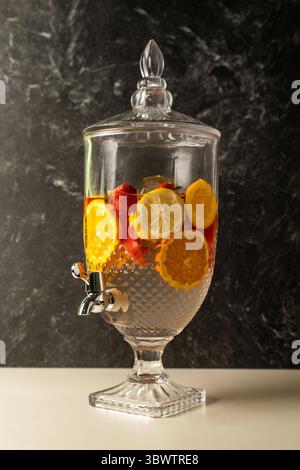 Großer Getränkespender aus Glas mit Wasserhahn, gefüllt mit Fruchtentgiftungswasser. Enthält frische Erdbeeren-, Zitronen- und Orangenscheiben mit Eis. Stockfoto