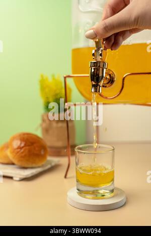 Frischer Orangensaft von Hand aus einem Glasspender in ein Glas gießen. Action-Nahaufnahme perfekt für Brunch, Party oder Event-Konzepte. Stockfoto