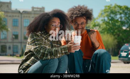 Zwei glückliche afroamerikanische Studenten multirassische Freunde afroamerikanische Frau Mädchen mit Jungen Mann Guy in der Stadt Universität College Schule gewinnen Stockfoto