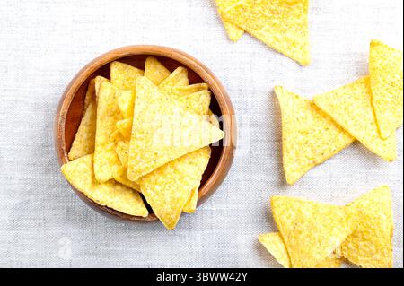Tortillachips in einer Holzschale auf Leinen. Klassische, knusprige Snacks aus Maistortillas, in dreieckige Keile geschnitten, in Öl frittiert. Stockfoto